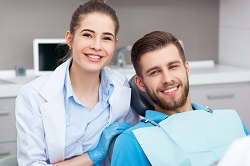 man smiling in dentist chair with female assistant, Sarasota, FL cosmetic dentistry